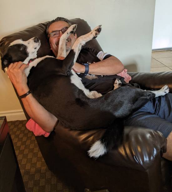 istock Man cradling his dog on his lap while reclining in a recliner. 2189435736