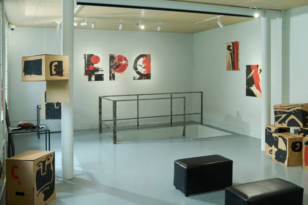 No people in spacious modern gallery hall with pair of black leather ottomans and group of creative artworks