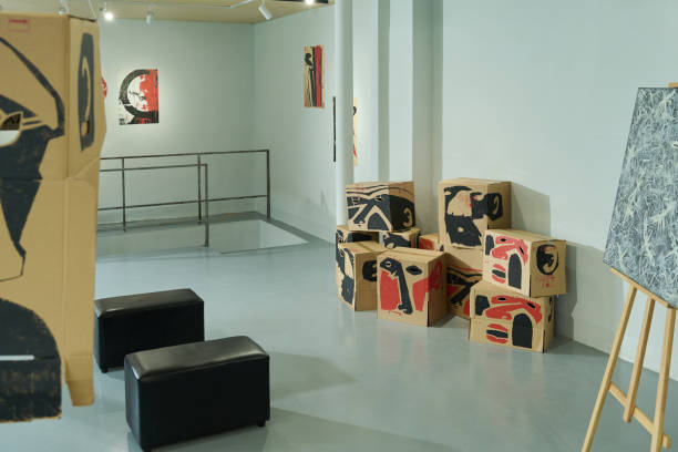 Part of spacious hall with ottomans, abstract painting and handmade cardboard boxes repurposed for installations