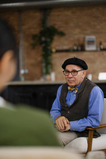 istock Senior Man in Vintage Attire Sitting and Conversing in Relaxed Indoor Setting 2189440015