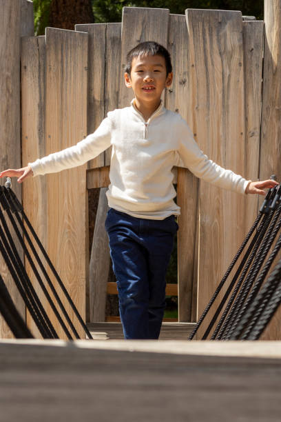 istock Young boy balancing on a rope bridge at playground 2189441059