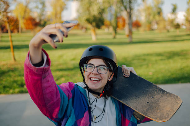 istock Young skater taking a selfie while holding her skateboard in a park 2189450669