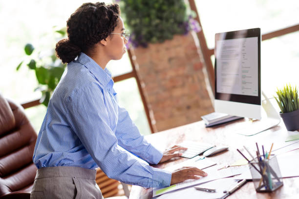 istock Young businesswoman in formal attire using computer at modern office workspace 2189453609