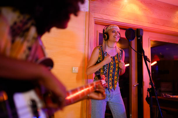 istock Singer girl with headphones singing a song while standing at studio. 2189455013
