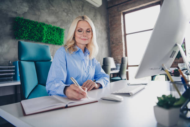 istock Mature professional businesswoman working in modern office setting, daytime natural lighting 2189455331