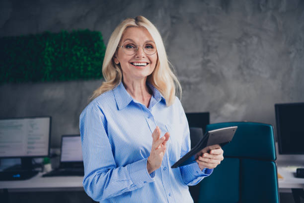 istock Confident senior businesswoman working in bright modern office environment holding tablet while smiling in natural daylight 2189455534