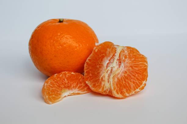 Overhead view of a half-peeled mandarin placed bottom-left on a light table with wide empty space for text.
