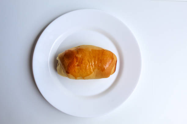 One simple baked bread, on white plate, isolated on white background, flat lay or top view