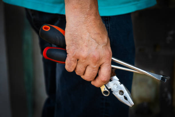 istock A close up of a hand holding pliers, a screwdriver, and other tools, symbolizing manual work or repair tasks 2189462484