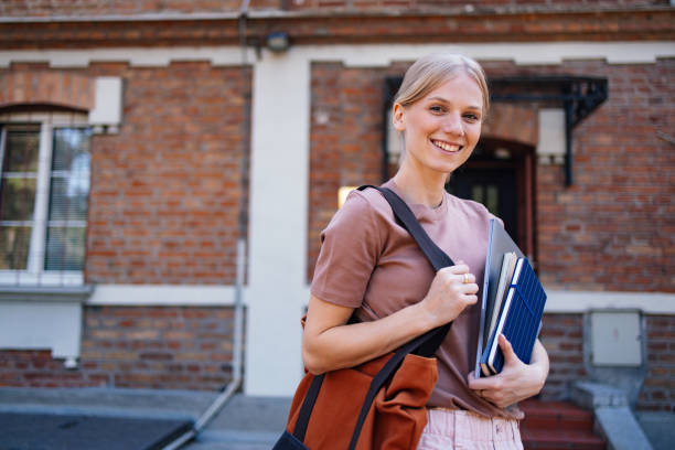 istock Smiling Student Holding Books Outside Historic Brick Building 2189464387