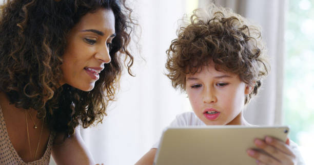istock Distance learning, education or tablet with mother and son in home for development, growth or study. Lesson, teaching or tutor with boy child student and single parent woman in apartment for homework 2189468061