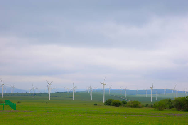 Windmills aerial view. Renewable energy. Large wind turbines with blades in field bright Green grassland.