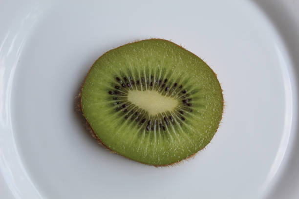 istock One slice of kiwi fruit, on white plate, isolated on white background, flat lay or top view 2189471370