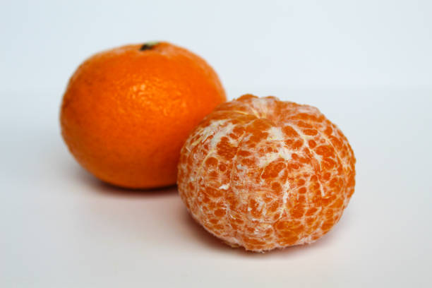 Three ripe orange tangerines with textured skin lie on a clean white background, creating a bright color accent.