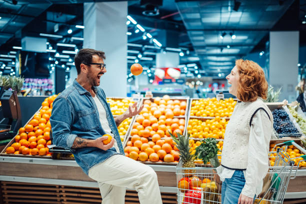 istock Cheerful couple juggling oranges while shopping in supermarket 2189472041