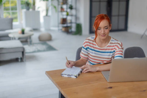 istock Young woman working on a laptop at home surrounded by a modern interior 2189472409