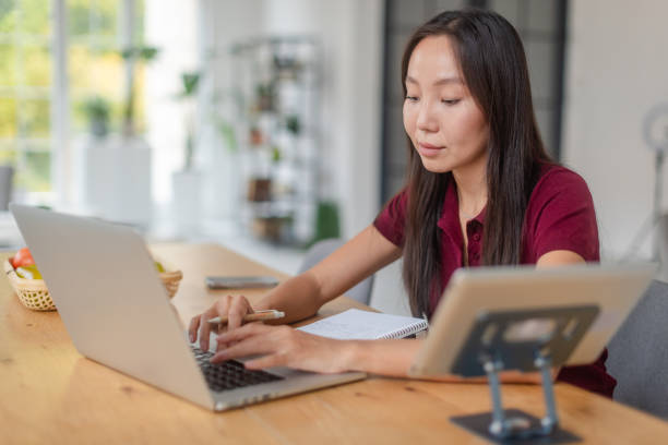 istock Focused Woman Working on Her Laptop and Taking Notes at Home 2189474027