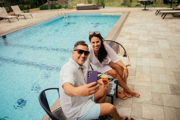 Mature couple taking selfies by the pool