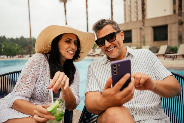istock Mature couple using smartphone next to swimming pool 2189480778