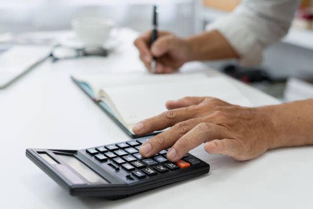 istock accountant reviews financial data using a calculator at desk in a busy office, ensuring accuracy in tax reporting and financial management. 2189484572