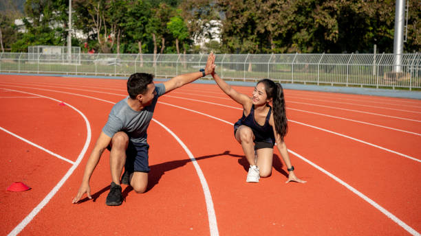 istock Two runners give high five while getting ready to run on a running track, training at a stadium 2189491858