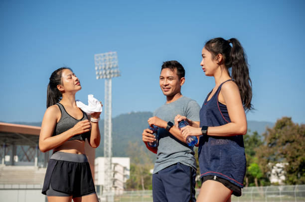 istock A group of Asian athlete runners enjoy a conversation while resting on a running track at a stadium. 2189491941