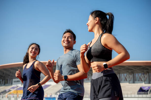 istock A group of cheerful Asian athlete runners enjoy a conversation while training at a stadium. 2189492075