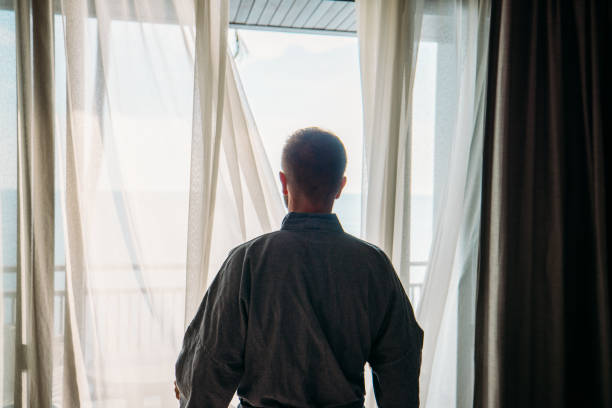 istock Man in Robe Looking Out Balcony Window 2189494259