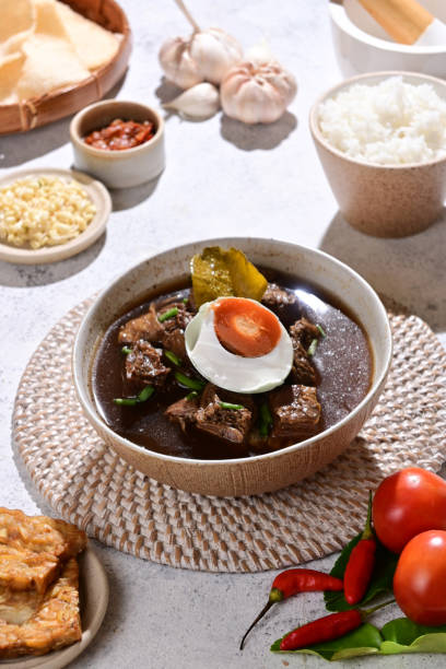 istock Rawon is a traditional Indonesian beef soup with a rich, black broth made from keluak nuts, aromatic spices, and herbs, typically served with rice and toppings like sprouts or sambal - selective focus 2189497747