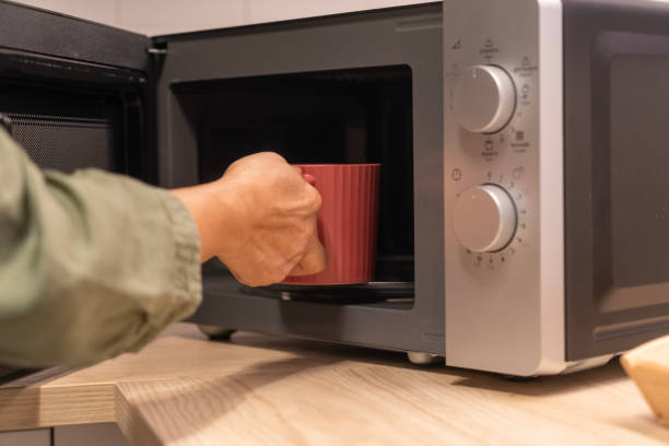 istock Female hand   places a red mug inside a microwave 2189509206