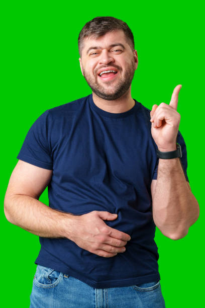 istock A man with a friendly smile gestures upwards while wearing a navy shirt against a bright green background 2189518537