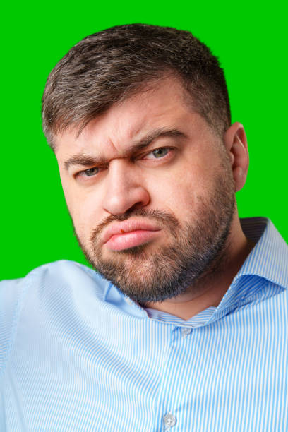 istock A man with a serious expression wearing a light blue shirt poses against a bright green background 2189519998