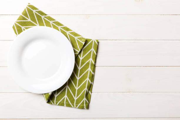 istock Top view on colored background empty round white plate on tablecloth for food. Empty dish on napkin with space for your design 2189521185