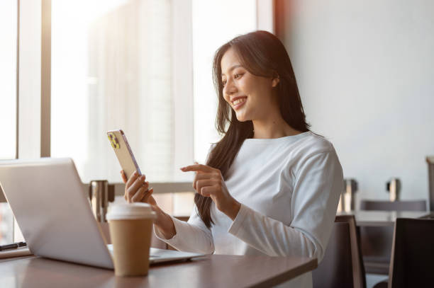 istock Attractive Asian woman reading messages on her smartphone while working remotely from a coffee shop. 2189522459
