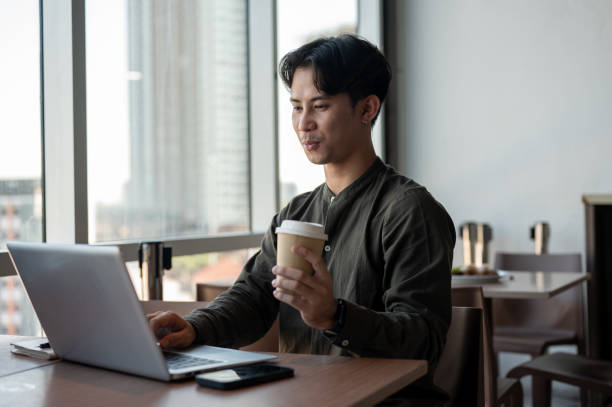 istock A positive Asian businessman enjoying a hot drink while working on his laptop, working remotely. 2189522708