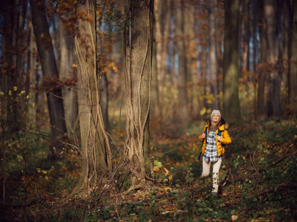 Smiling female backpacker enjoying while walking through the woods in autumn day. Photographed in medium format.