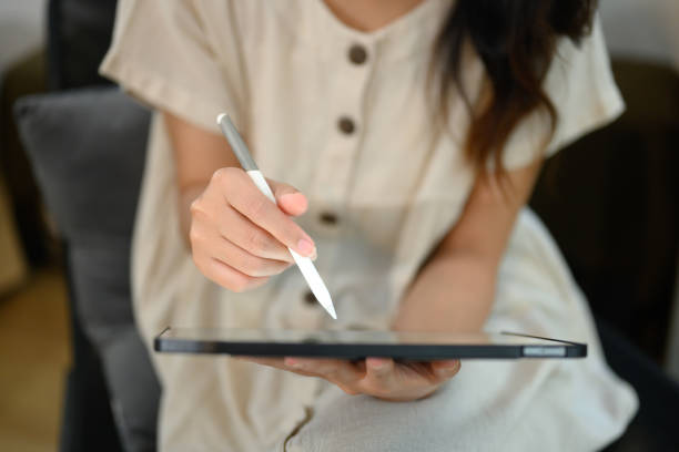 istock Asian female freelancer using stylus pen writing or drawing on digital tablet screen 2189528351