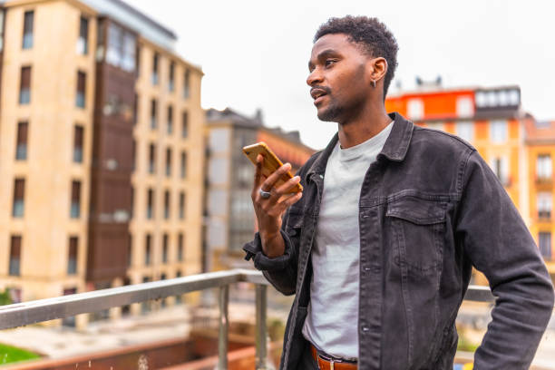 istock African man holding mobile sending a voice message at city 2189529261