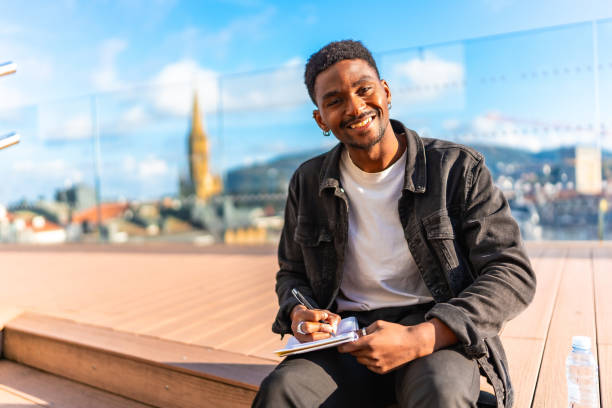 istock Happy african man writing notes sitting outdoors 2189529693