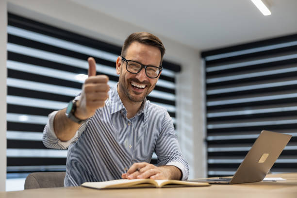 istock Confident Businessman Giving Thumbs Up in Modern Office Environment 2189534724