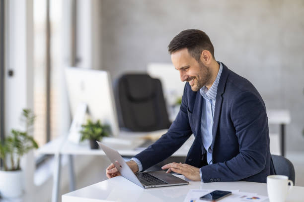 istock Smiling Business Professional Using Laptop At Modern Office Desk 2189534792