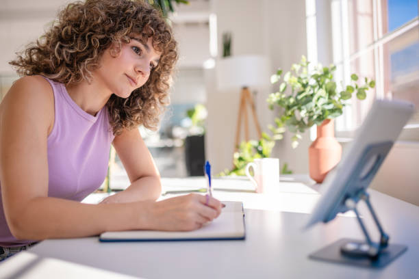 istock Woman writing in notebook in a bright and modern workspace 2189535302