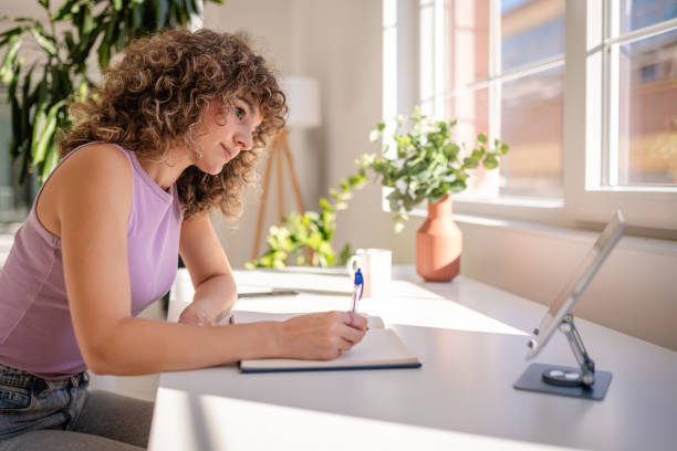 istock Young woman writing in a notebook at a bright home office desk 2189535518