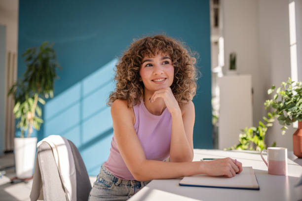 istock Smiling young woman relaxing at sunny desk in creative workspace 2189535962