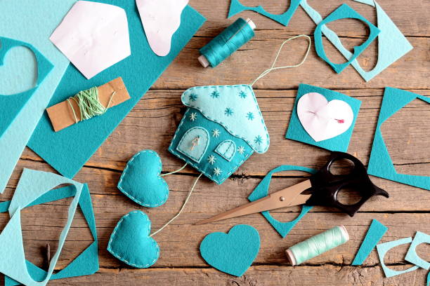 istock Felt house with hearts decoration, tools and materials for sewing, paper patterns on old wooden background 2189536094