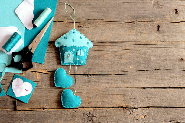 istock Felt house with hearts decor, scissors, thread, needle, paper patterns on old wooden background with copy space for text 2189536095