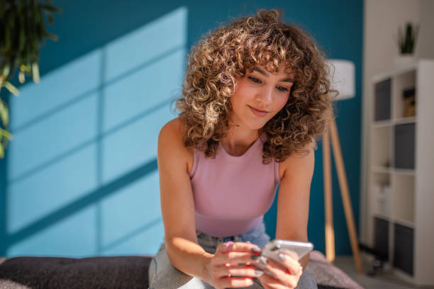 istock Young woman using phone indoors with natural light and stylish decor 2189536271