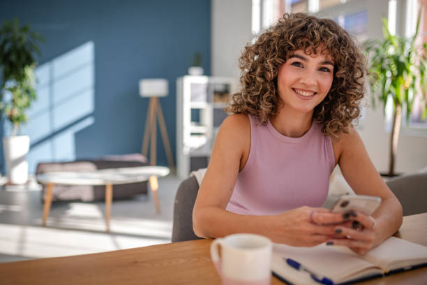 Young woman smiling while using smartphone at a stylish indoor workspace