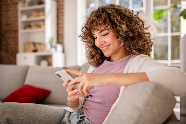 istock Woman Smiling While Browsing Her Phone at Home on the Sofa 2189537554
