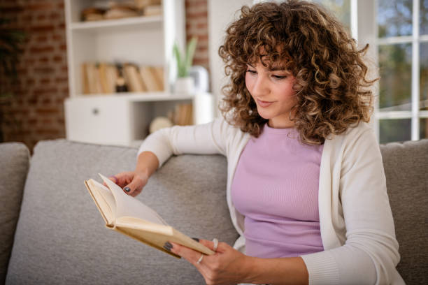 istock Woman Relaxing Indoors Reading A Book On A Comfortable Sofa 2189537969